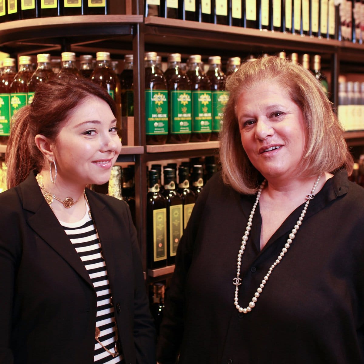 Valentina Musco Puleo and Agata Musco smiling in the store, in front of shelves of Agata & Valentina olive oil